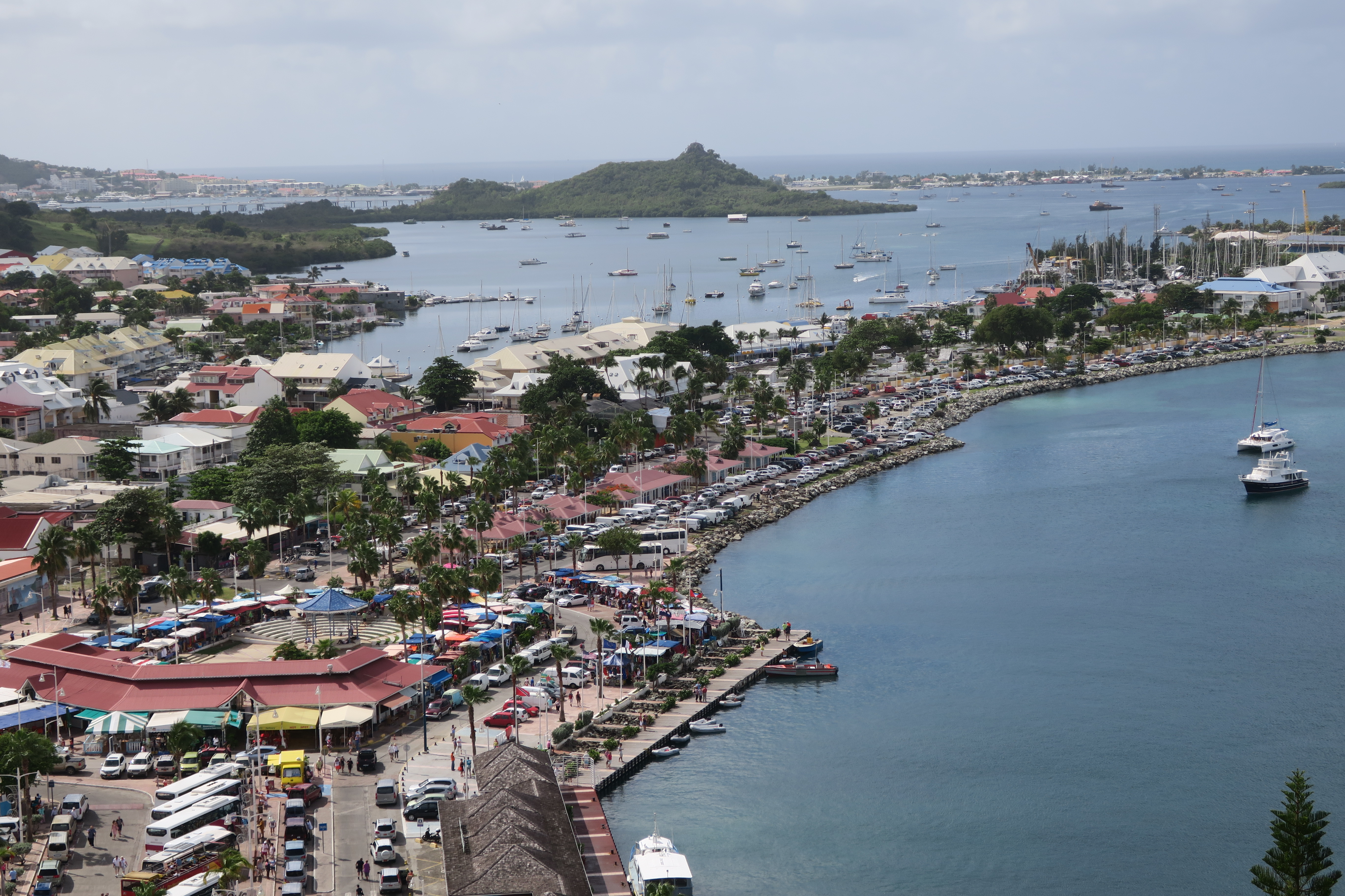 Wide elevated view over Marigot’s waterfront, low buildings, boats and surrounding bay.